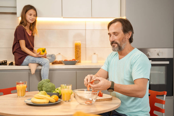 Adult man with daughter preparing salad in the kitchen - Photo, Image