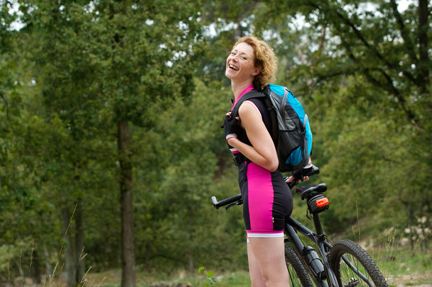 Весела жінка посміхається з велосипедом на відкритому повітрі
 - Фото, зображення
