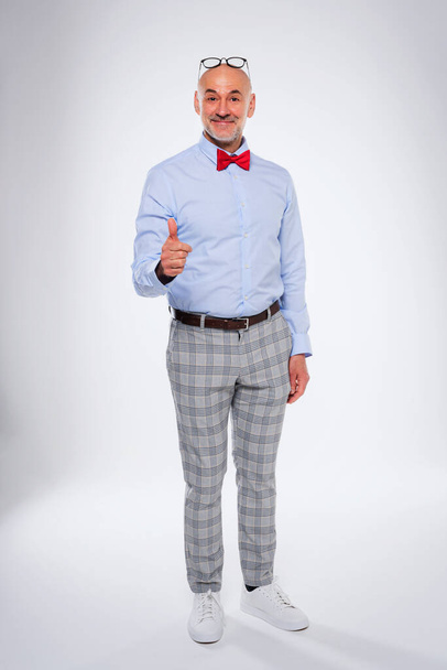 Full length of smiling businessman giving thumbs up while standing at isolated white background and giving thumbs up. - Foto, Imagem
