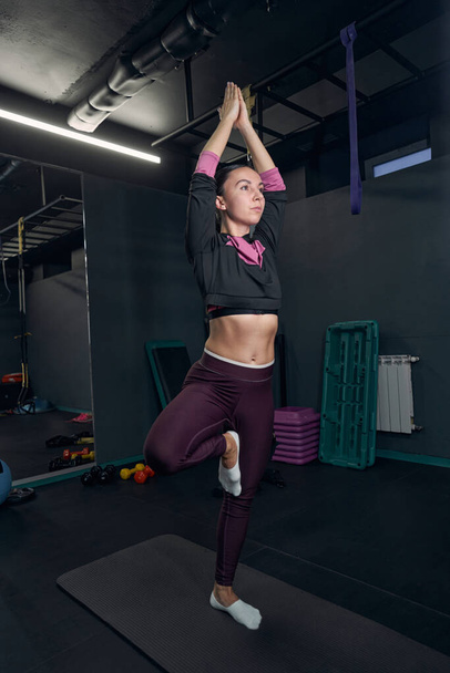 Concentrated female person doing yoga in the gym - Foto, afbeelding