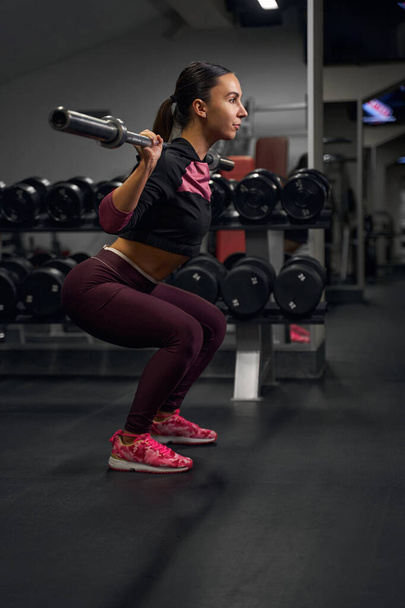 Profile photo of sportswoman lifting heavy weights - Foto, immagini