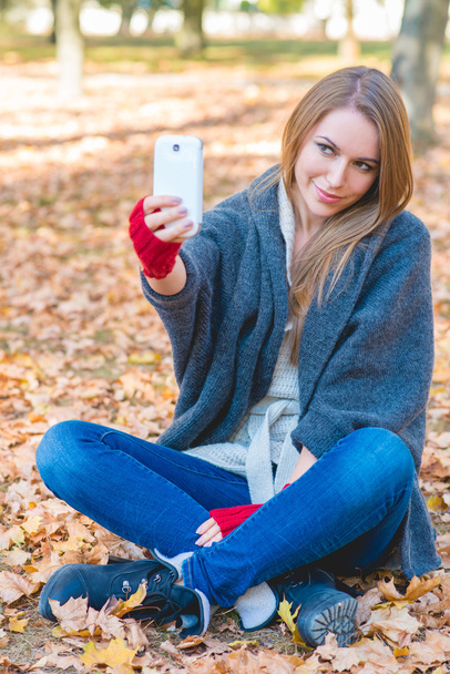 uśmiechający się przy selfie w parku jesień - Zdjęcie, obraz