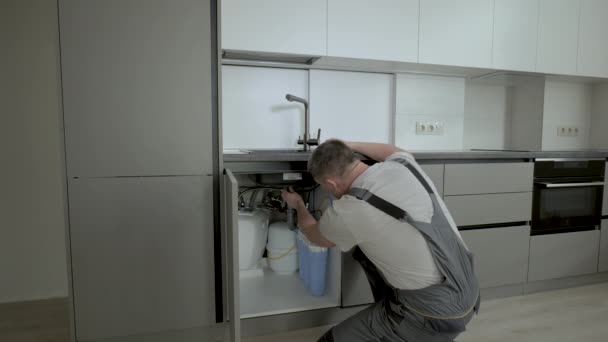 Encanador masculino fixação de tubos sob a pia na cozinha - Filmagem, Vídeo