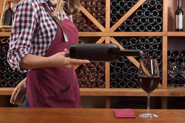 κορίτσι από ένα μπουκάλι ρίχνει κόκκινο κρασί σε ένα ποτήρι, γεύση έννοια, closeup - Φωτογραφία, εικόνα