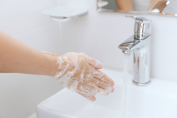 Lavarse las manos bajo el grifo de agua corriente. Concepto de higiene detalle de la mano. Lavarse las manos frotándose con jabón para prevenir el virus de la corona, higiene para dejar de propagar el virus de la corona en el baño público - Foto, imagen