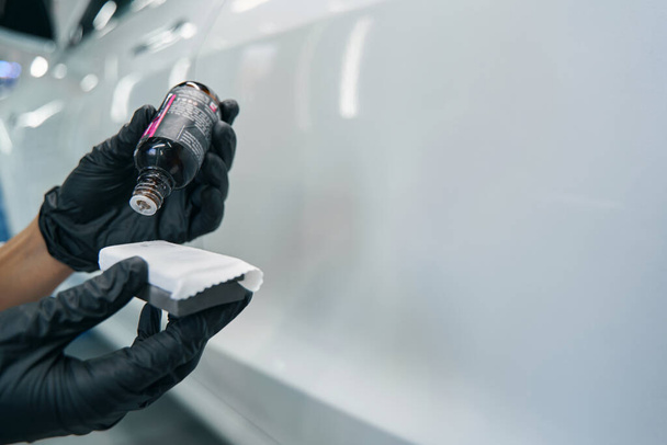 Worker in nitrile gloves preparing tool for car polishing - Photo, image