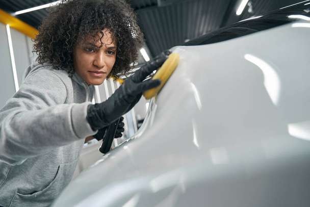 Focused service station worker polishing car exterior - Foto, afbeelding
