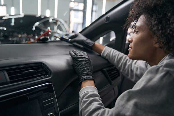Technician seated in car examining windshield repair device - Фото, зображення