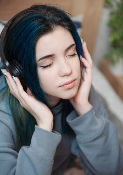 Молодая девушка-подросток с голубыми волосами и наушниками  - Фото, изображение