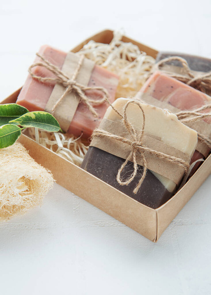 Handgemaakte zeep repen en groene bladeren in doos op stro  - Foto, afbeelding