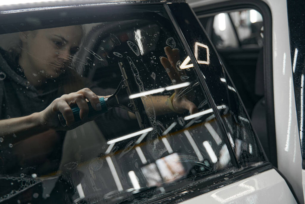 Experienced service station employee fixing PPF on car glass - Fotó, kép
