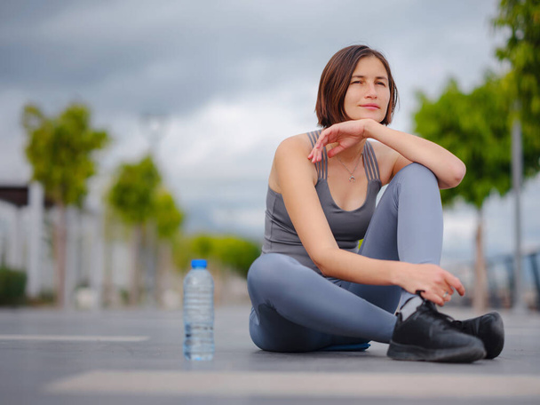 outdoor sports, workout and wellness concept. asian young strong, confident woman in sportive clothes Relaxing After Fitness Workout In Park. Female runner taking break from running sport. - Photo, Image