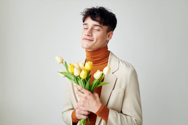 Photo young boyfriend in white jacket with a bouquet of yellow flowers elegant style Lifestyle unaltered - Fotó, kép