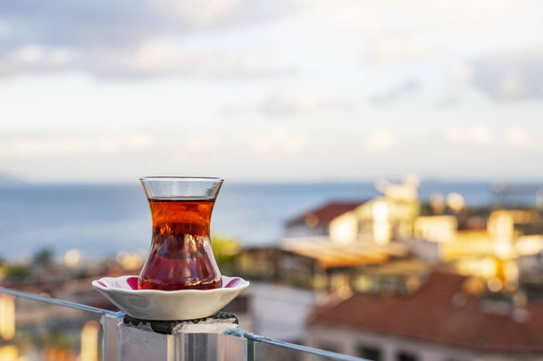 Ζεστό μαύρο τούρκικο τσάι. Ένα φλιτζάνι τούρκικο τσάι με ένα πιατάκι στο φόντο του Βοσπόρου την αυγή. - Φωτογραφία, εικόνα