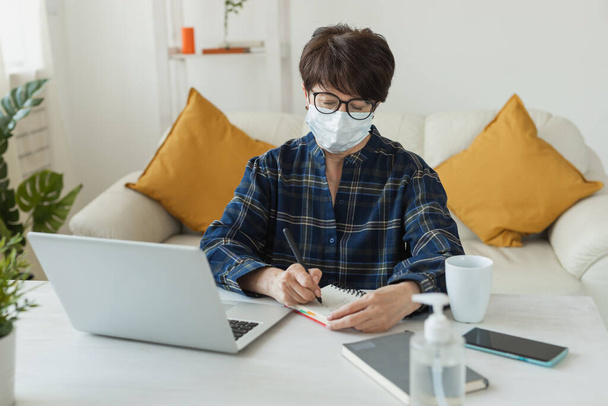 Formação online e trabalho freelance. Computador, laptop e mulher de meia-idade funciona remotamente. pandemia de coronavírus no mundo. Bloqueio - Foto, Imagem