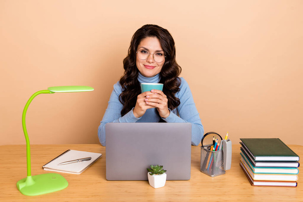 Photo of dreamy pretty woman wear blue sweater spectacles drinking tea typing device isolated beige color background - Foto, Imagem