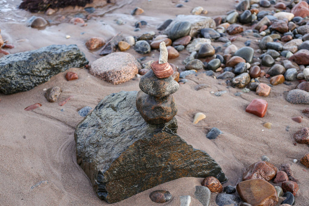 Piedra que equilibra el apilamiento de piedra cerca del hermoso mar báltico en la arena costa. Foto tomada en un cálido día nublado. - Foto, imagen