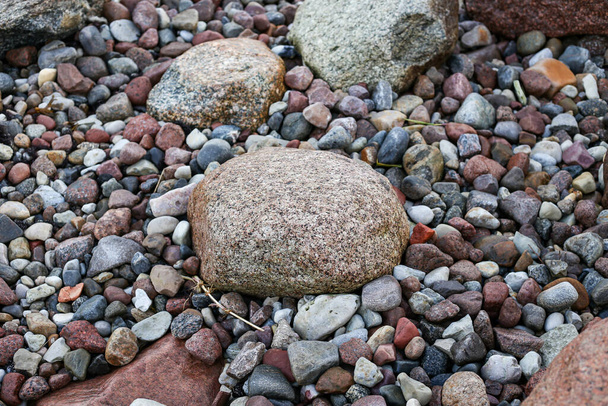 Vista fotografica da vicino con piccole e grandi rocce su una spiaggia. Foto scattata in una giornata autunnale nuvolosa. - Foto, immagini