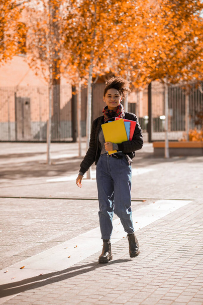 Dívka s knihami v rukou kráčející po ulici - Fotografie, Obrázek