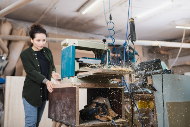 Sawdust and bench thicknesser near blurred carpenter working in workshop  - Фото, изображение