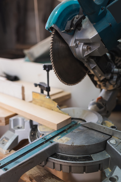 Close up view of miter saw and wooden board in workshop  - Fotoğraf, Görsel