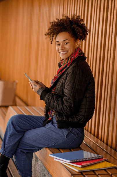 A pretty dark-skinned girl with a phone - Фото, зображення