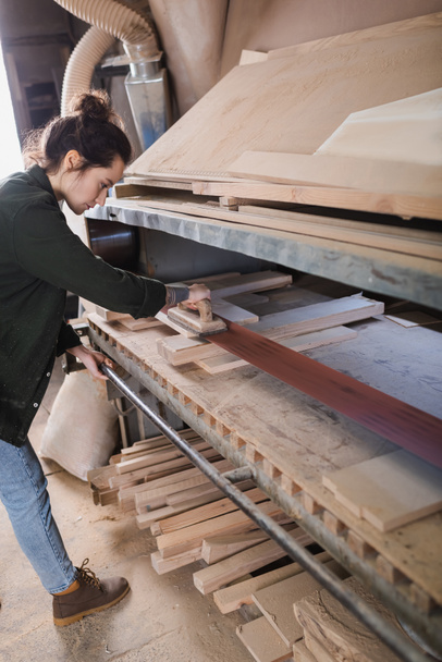 Side view of carpenter polishing planks in workshop  - Φωτογραφία, εικόνα