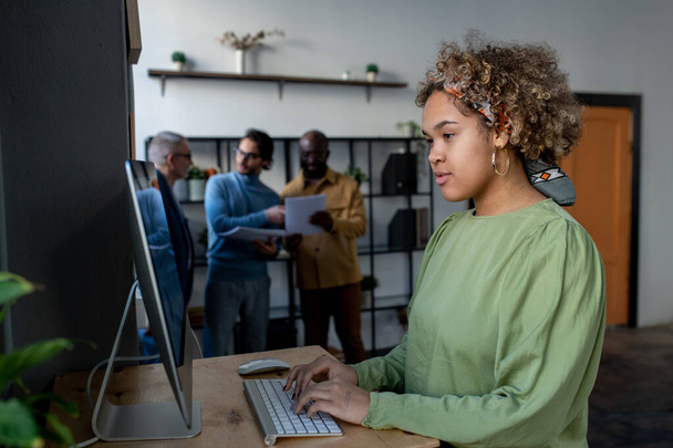 Young pretty biracial businesswoman looking at computer screen - Photo, Image