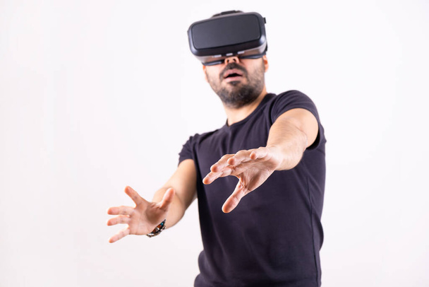 Een jongeman met een VR-bril die opgewonden portretten maakt. Virtual reality, toekomstige technologie, educatie video gaming - Foto, afbeelding