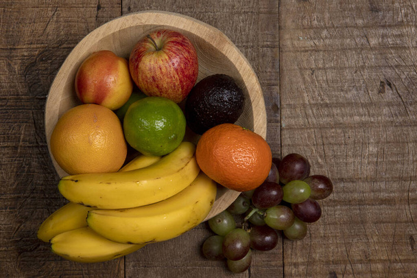 Cuvette en bois aux fruits variés, sur table rustique en bois. Espace pour le texte
 - Photo, image