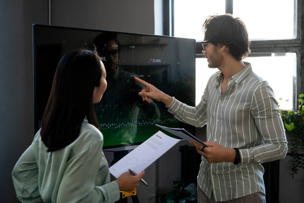 Fiatal magabiztos férfi közgazdász mutat grafikon interaktív képernyőn - Fotó, kép