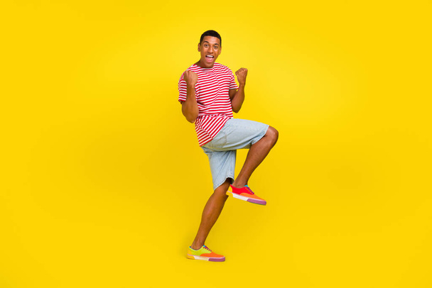 Full length photo of delighted guy raise fists up enjoy rejoice win fan isolated over bright yellow color background - Фото, зображення