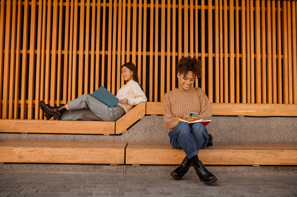 Two girls sitting in pavillion and studying - Foto, afbeelding