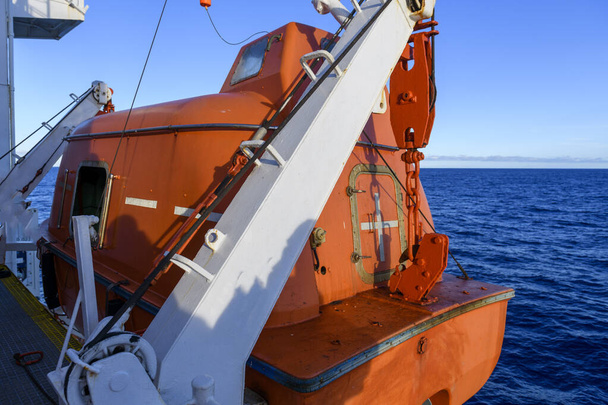 Das orangefarbene Rettungsboot wird zu Wasser gelassen. Schiffsdrill aufgeben. Rettungsbootausbildung. Mann über Bord. - Foto, Bild