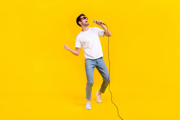 Full body photo of cool young brunet guy sing wear eyewear t-shirt jeans shoes isolated on yellow background - Photo, image
