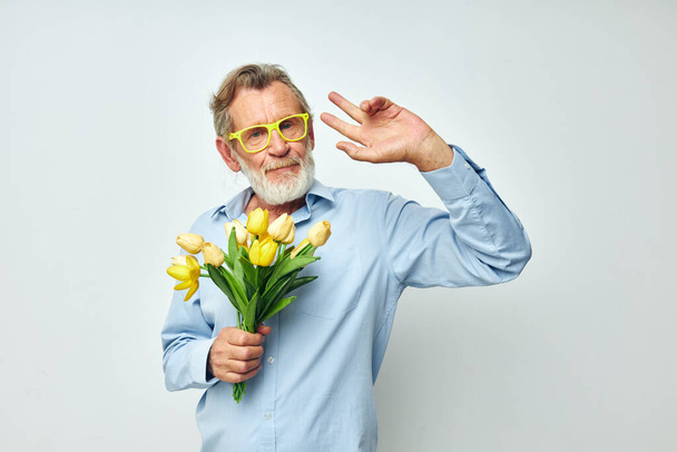 elderly man a bouquet of flowers with glasses as a gift light background - Foto, Imagem