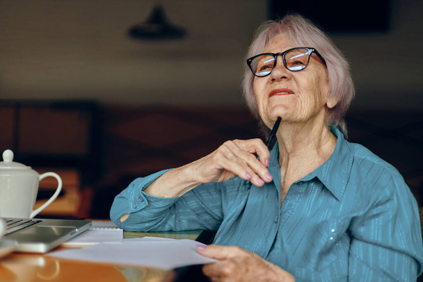 Happy senior woman documents work sheet of paper and pen Freelancer works unaltered - 写真・画像