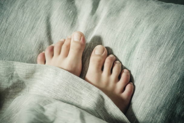 voeten onder de deken close-up - Foto, afbeelding