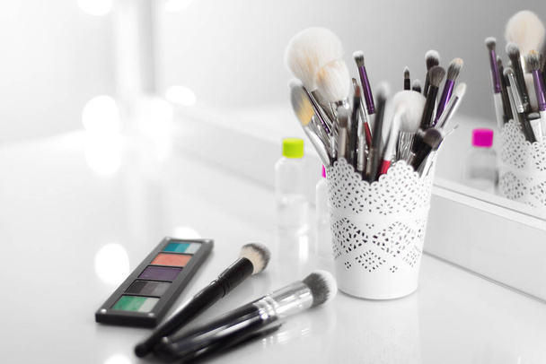 op de make-up tafel zijn make-up penselen, een palet met schaduwen - Foto, afbeelding