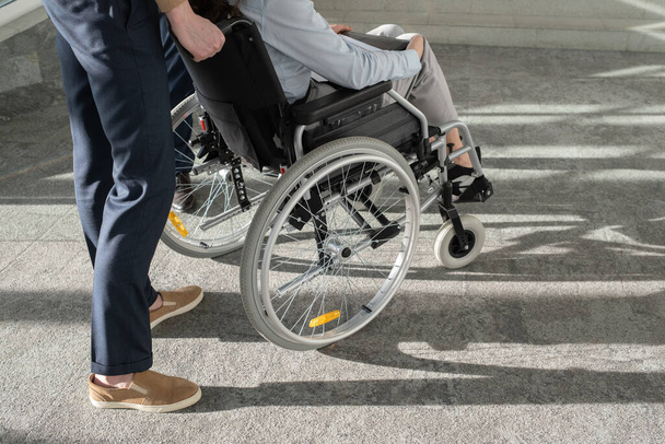 Молодой элегантный бизнесмен, стоящий в инвалидной коляске с коллегой - Фото, изображение