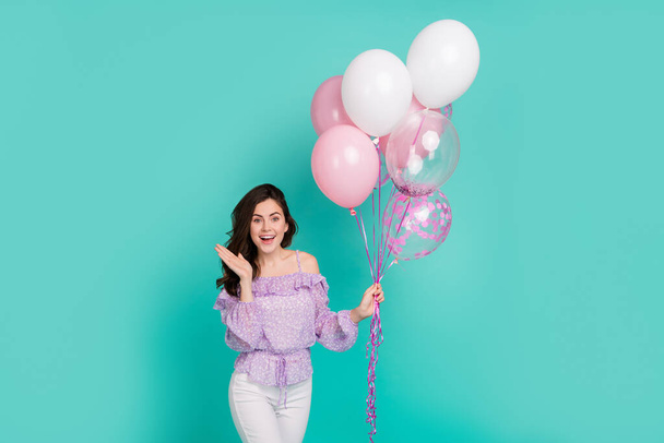 Portrait of pretty satisfied girl hold balloons raise hand unbelievable isolated on turquoise color background - Photo, image