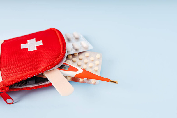 Cestovní nebo domácí lékárnička s teploměrem, pilulky na modrém pozadí. Nápis s prostorem pro text - Fotografie, Obrázek
