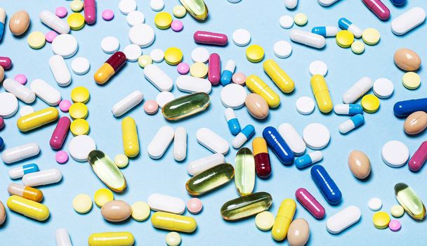 Різноманітність ліків в капсулах і таблетках різних кольорів на синьому фоні. Медична концепція. фармацевтичних
 - Фото, зображення