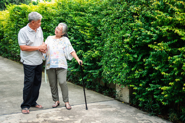 Szczęśliwa para seniorów spacerująca razem w ogrodzie. Starzy starzy ludzie używają kija do chodzenia, by pomóc im zachować równowagę. Pojęcie miłości i opieki nad rodziną i ubezpieczenia zdrowotnego dla rodziny - Zdjęcie, obraz