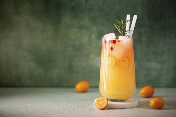 freshly squeezed orange juice with kumquat slices and ice in a glass, close-up - Foto, Imagem