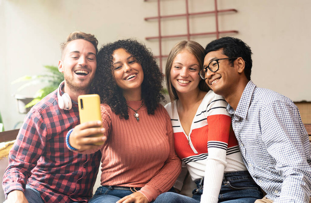 スマートフォンで自撮りをする若い友達グループ – 多文化・多民族の友達と楽しいビデオ通話をするコミュニティの概念 – 多様性と友情の概念 - 写真・画像