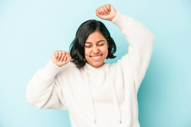 Young latin woman isolated on blue background celebrating a special day, jumps and raise arms with energy. - Photo, image