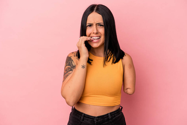 Young caucasian woman with one arm isolated on pink background biting fingernails, nervous and very anxious. - Photo, Image