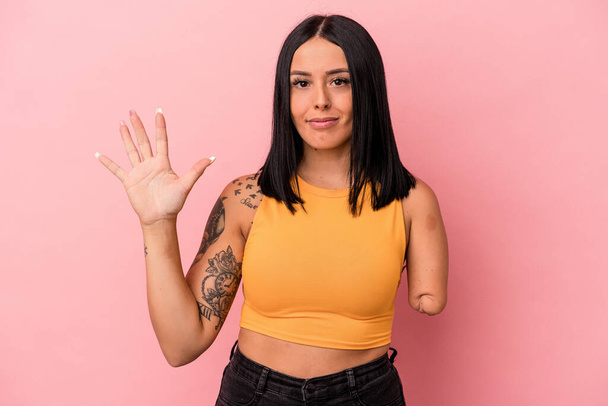 Young caucasian woman with one arm isolated on pink background smiling cheerful showing number five with fingers. - Photo, Image