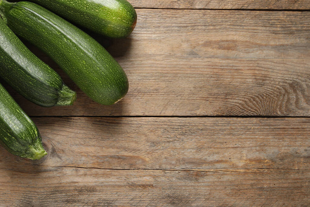 Raw ripe zucchinis on wooden table, flat lay. Space for text - Photo, Image